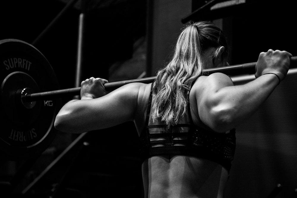 Sporter van achteren met een barbell op de schouders, in zwart-wit