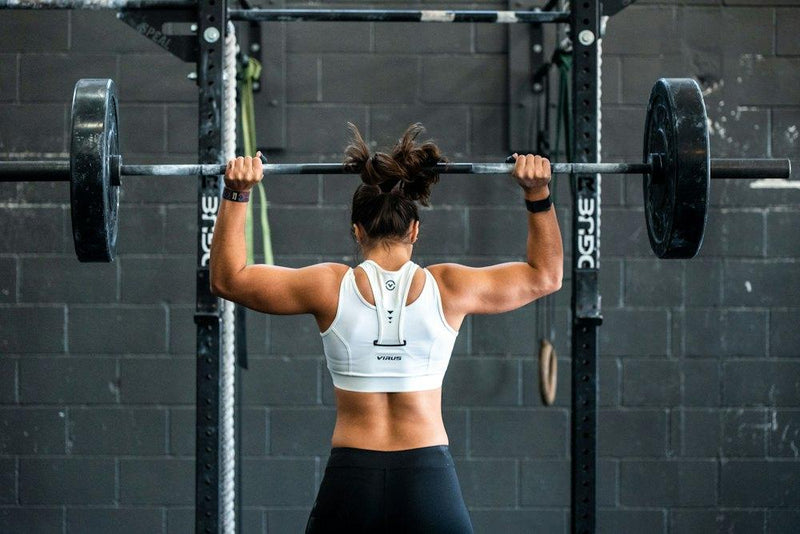 Sporter van achteren met een barbell in een squatrek