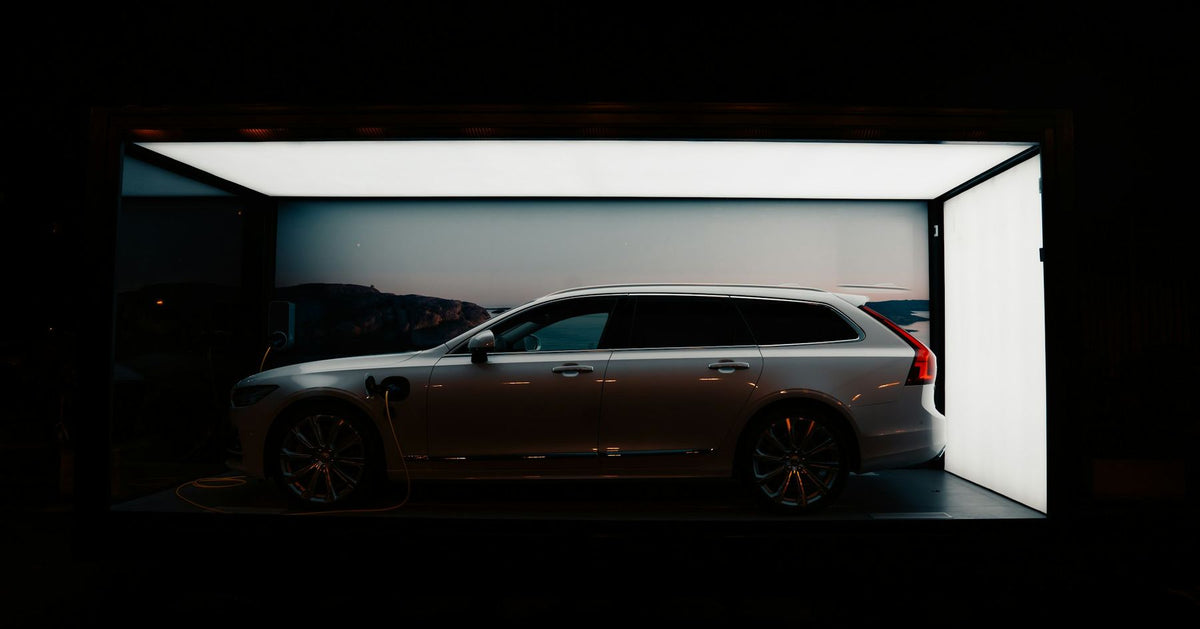 Witte stationwagen in een verlichte showroombox, 's avonds