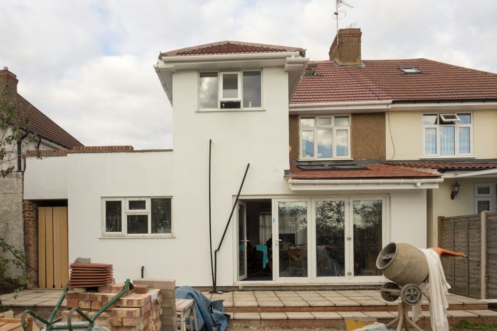 Na: nieuwe witte aanbouw over twee verdiepingen met een brede schuifpui