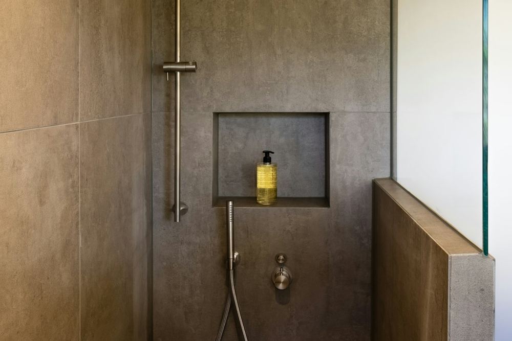 Na: inloopdouche in betonlook met een nis en een glazen wand