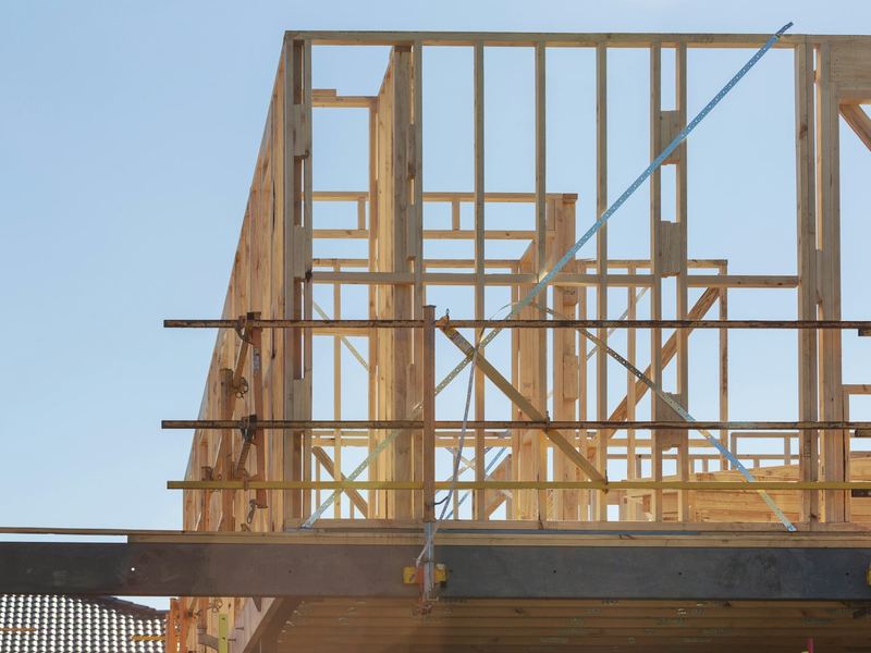 Houten skelet van een nieuwe woning tegen een blauwe lucht