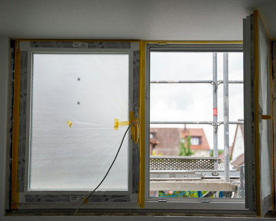 Een nieuw kozijn met afgeplakt glas, buiten staat de steiger