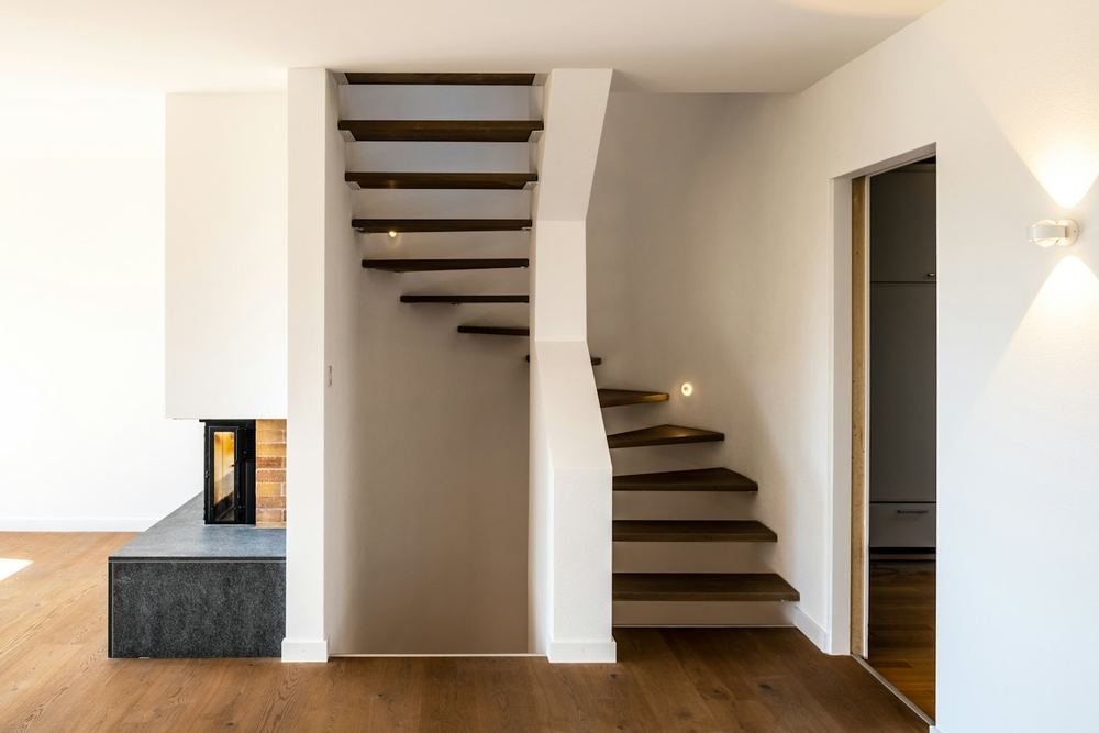 Na: zwevende eiken trap naast de haard, nieuwe houten vloer