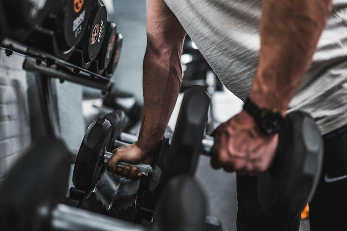 Twee handen pakken dumbbells uit het rek