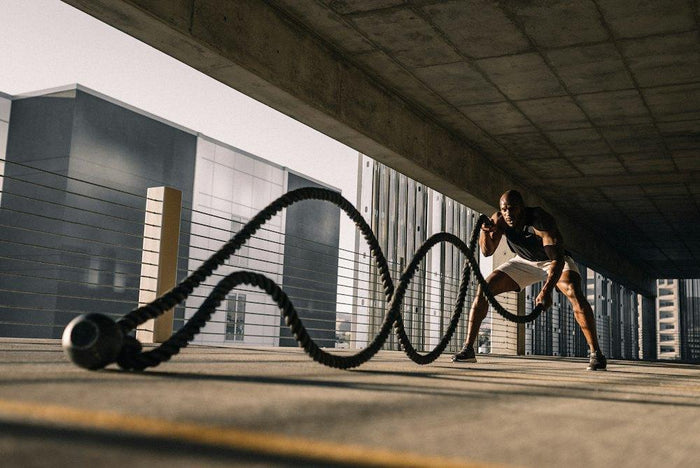 Sporter met battle ropes in een industriële ruimte
