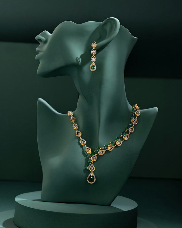 Gouden collier met druppels van diamantjes en smaragden op een groene buste