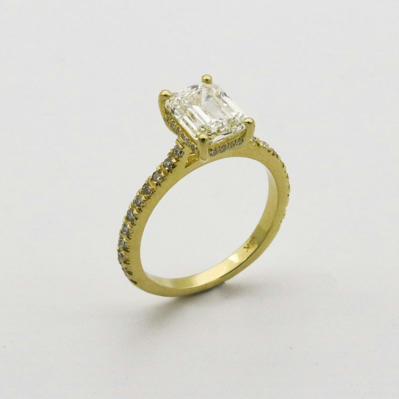 Geelgouden ring met een grote rechthoekige diamant in vier klauwen en kleine diamanten in de band