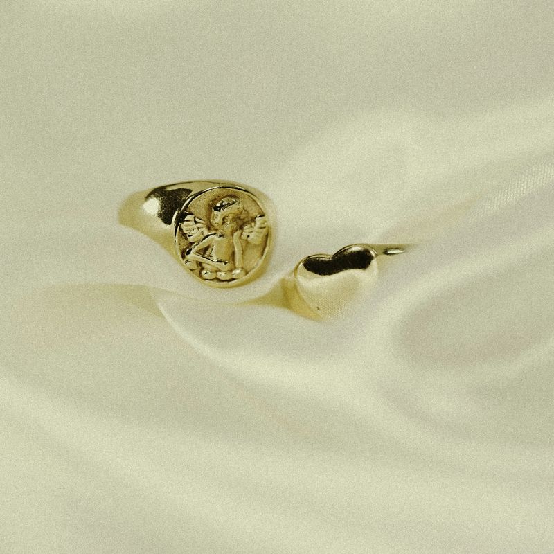 Gouden zegelring met een gegraveerd motief op een witte zijden doek