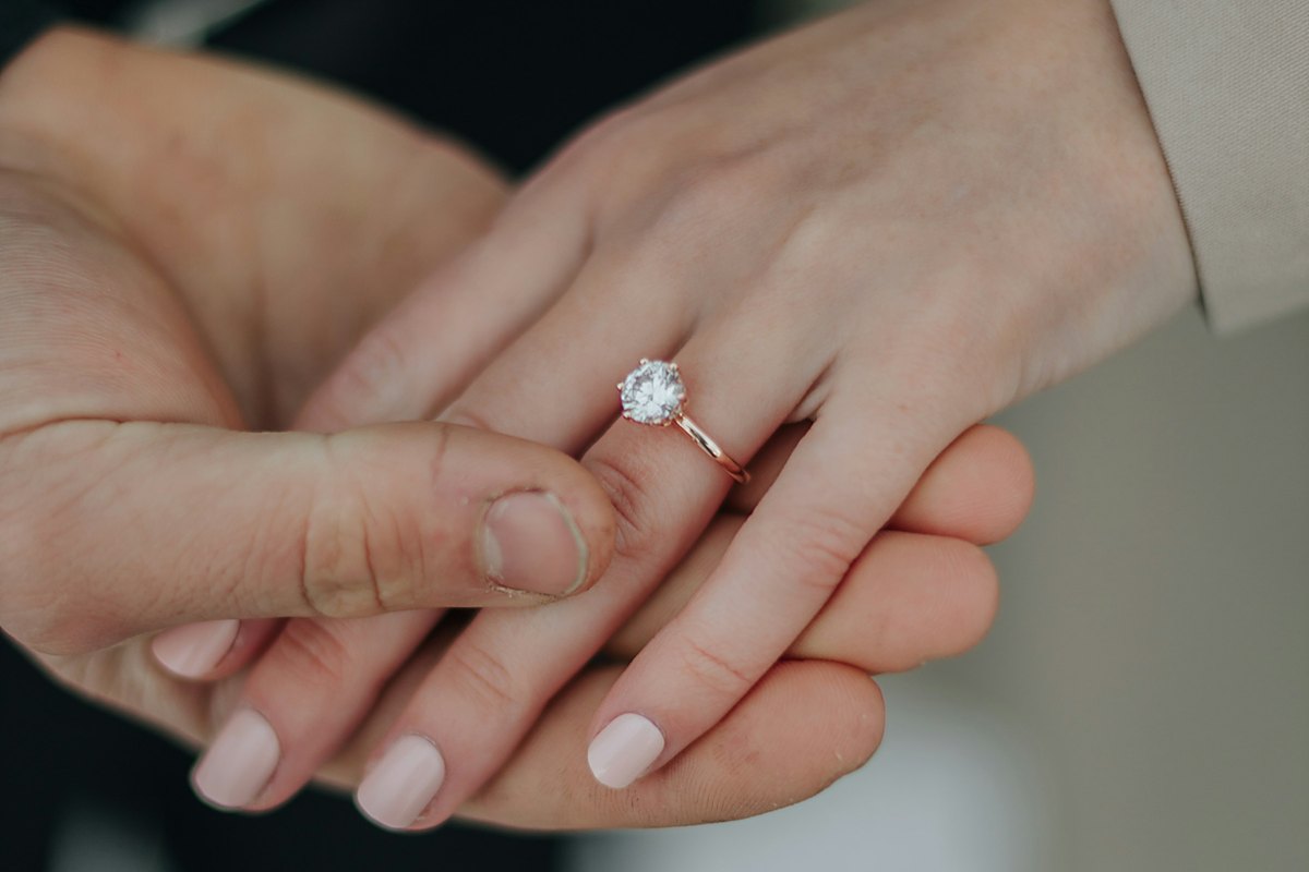 Twee handen in elkaar, aan de vinger een ring met een briljant