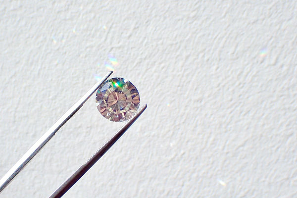 Een geslepen diamant in een pincet tegen een witte achtergrond