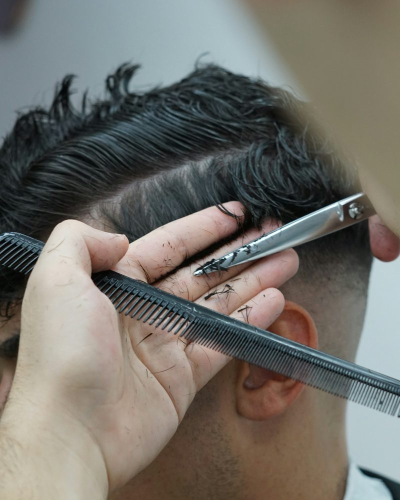 Een herenkapsel wordt met schaar en kam bijgewerkt