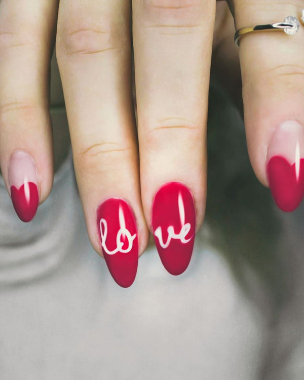 Rode amandelnagels met het woord love in witte letters en roze tips