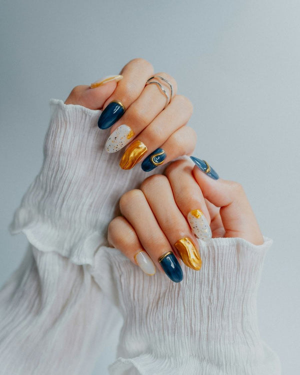Nail art in donkerblauw, oker en wit met gouden accenten