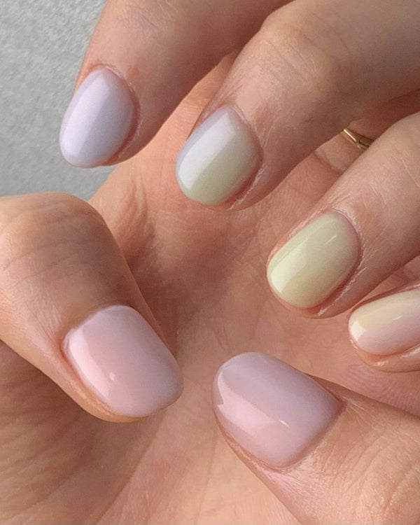 Korte nagels in verschillende pasteltinten: lila, mint, vanille en roze