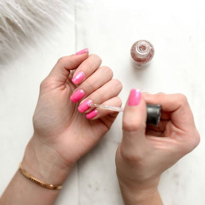 Nagels worden roze gelakt met een glittertopje