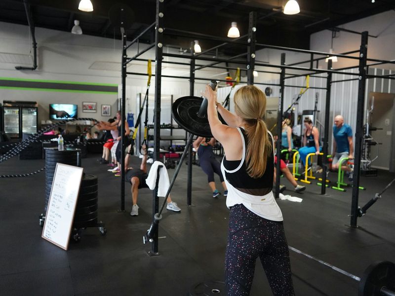 Een small group les in volle gang: mensen trainen met suspension trainers, een halter en rekstokken