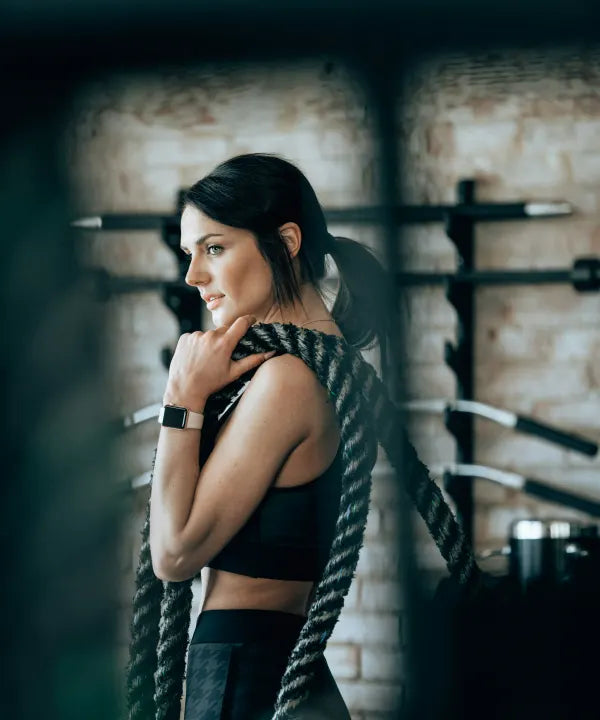 Sporter met een battle rope over haar schouder in de sportschool