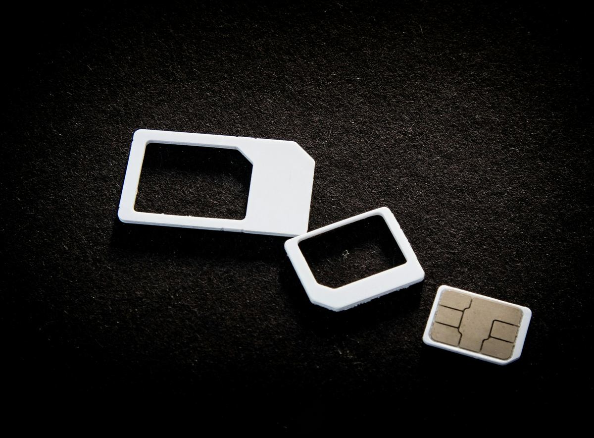 Een simkaart met twee witte adapters op een donkere ondergrond